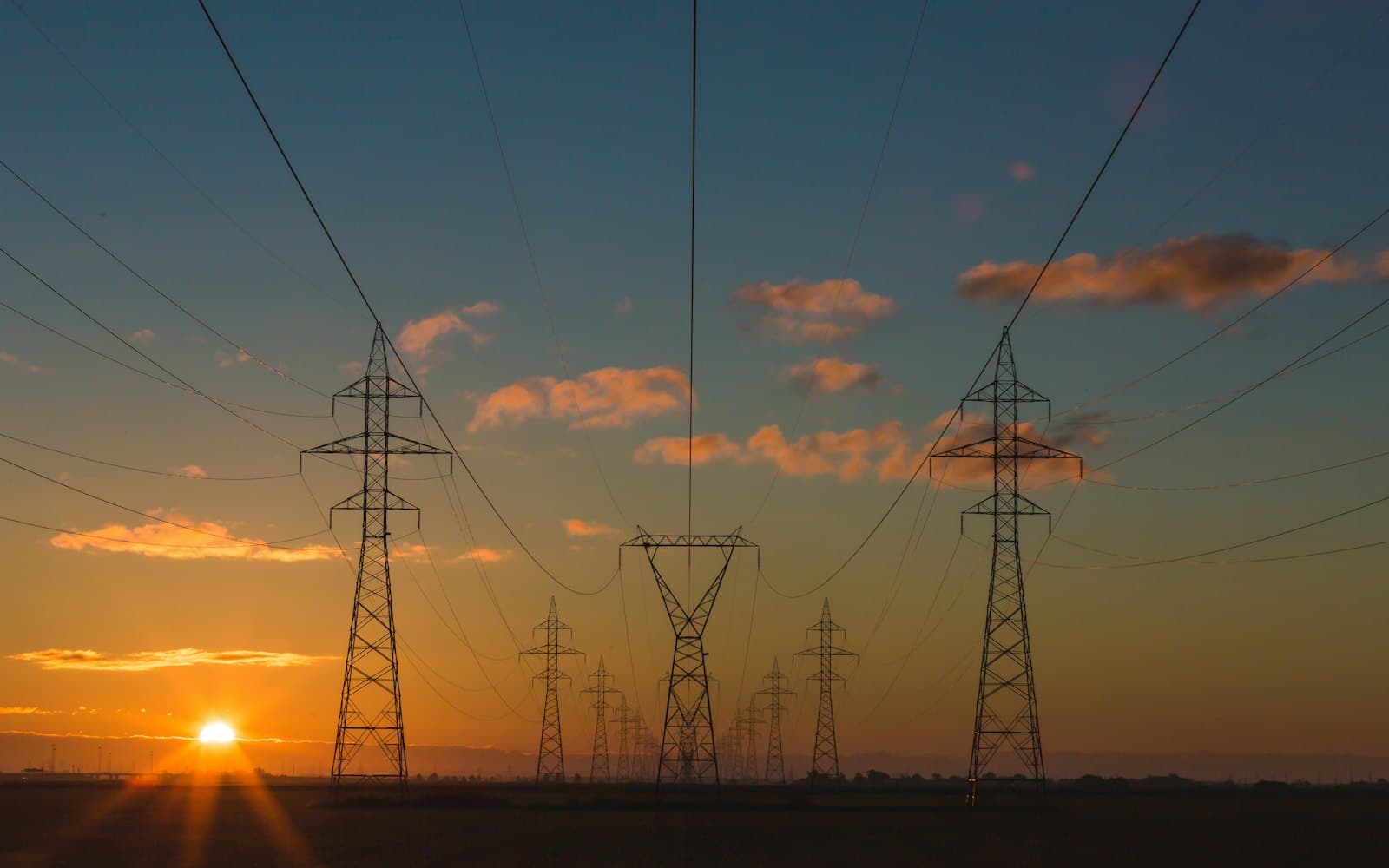 High-voltage transmission pylons at sunset.
