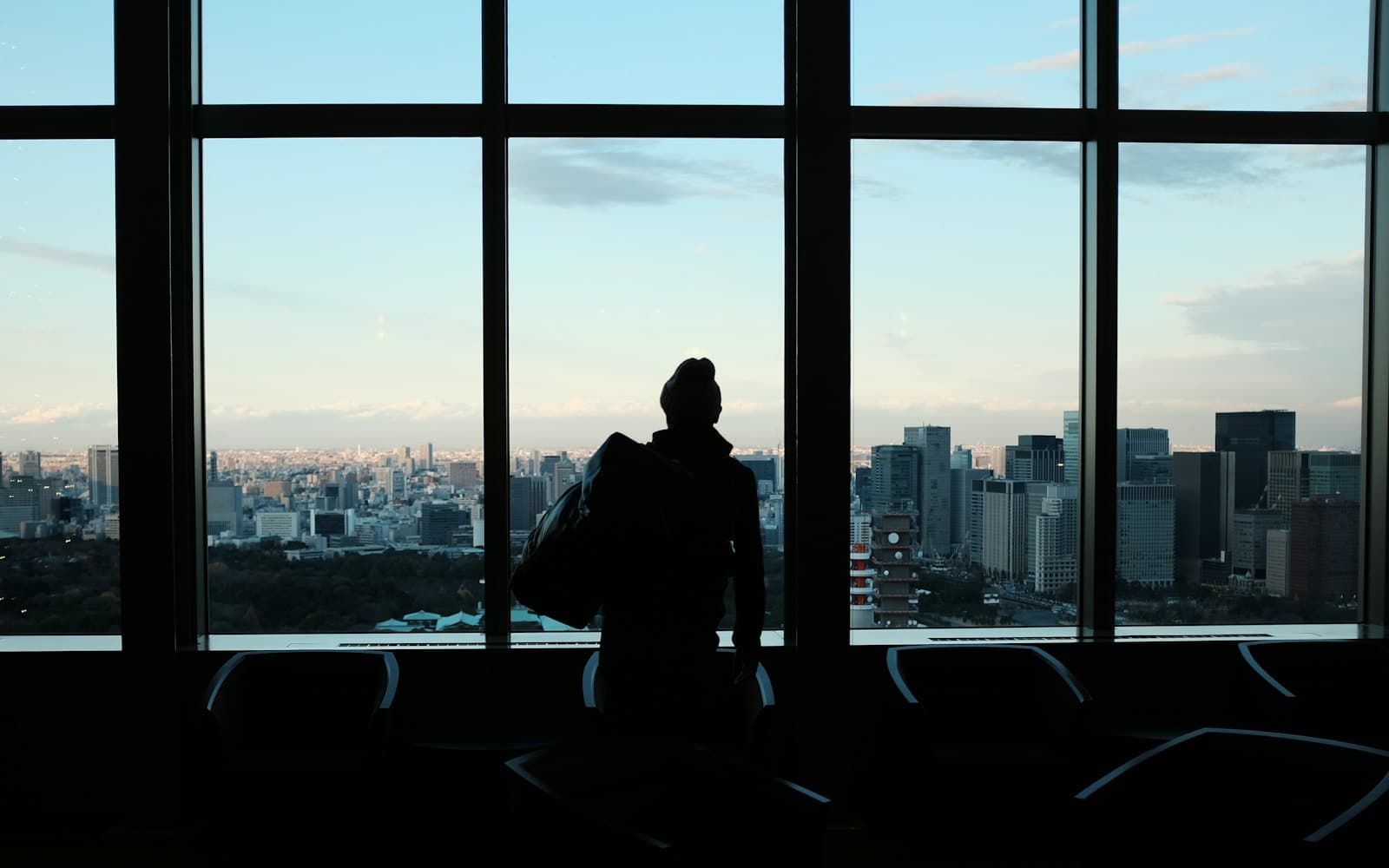 An executive looking out over a city skyline while weighing up the business outcome to aim for.
